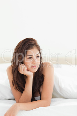 Woman lying at the end of the bed looking slightly to the side