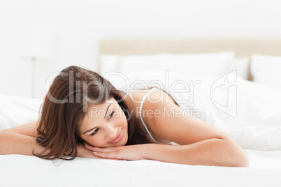 Woman lying at the end of the bed with her head looking to the s