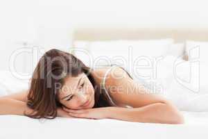 Woman lying at the end of the bed with her head looking to the s