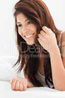 Close up of woman smiling with a hand in her hair while lying on