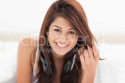 Woman looking straight ahead while smiling and clasping her hair