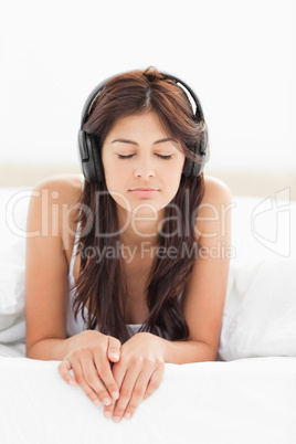 Woman at the edge of the bed listening to music with her eyes cl