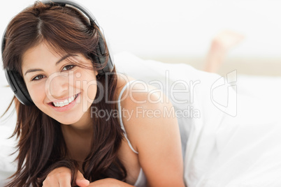 Woman lying down with a quilt over her, while listening to her h