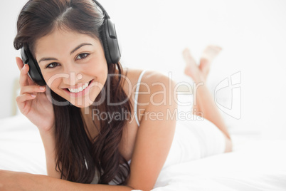 Woman with crossed legs smiling while listening to her headphone