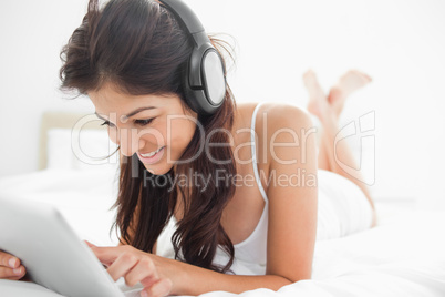 Woman with her legs crossed on the bed listening to headphones,