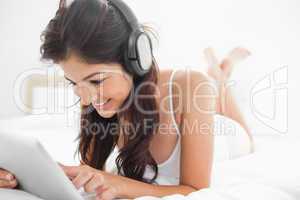 Woman with her legs crossed on the bed listening to headphones,