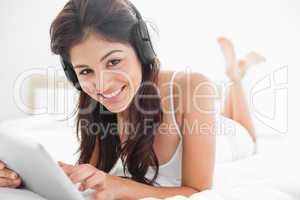 Woman using a tablet and headphones while looking up and smiling