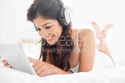 Woman using a tablet and headphones with her legs crossed