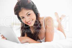 Woman with a tablet and headphones looking forward and smiling