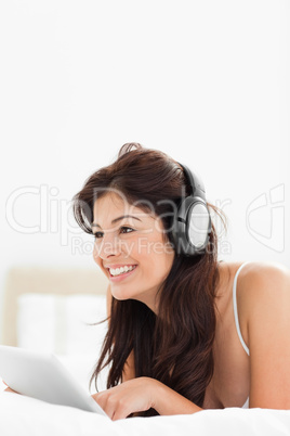 Woman looking forward and smiling while using a tablet and headp