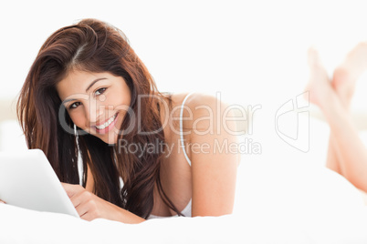 Woman holding a tablet, while looking up and smiling with her le