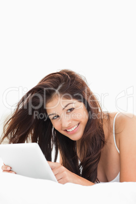 Close up, woman interacting with a tablet while lying on a bed