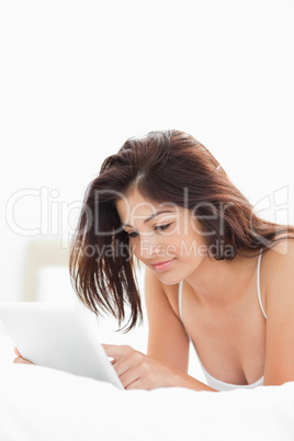 Woman using a tablet while lying on the bed