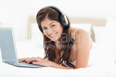 Woman looking forward and smiling while browsing though a laptop