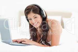 Woman looking forward and smiling while browsing though a laptop