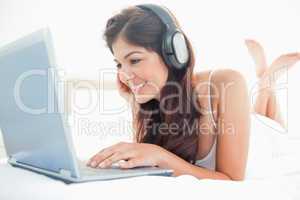 Woman watching her laptop screen and listening to her headphones