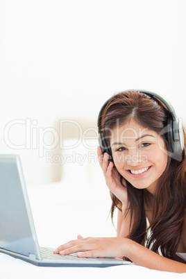 Close up, woman using headphones and laptop on a bed