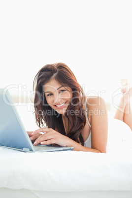 Vertical, Woman lying on a bed, with raised crossed legs, lookin