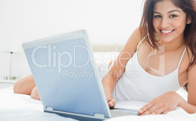 Woman looking forward as she holds her laptop and relaxing on he
