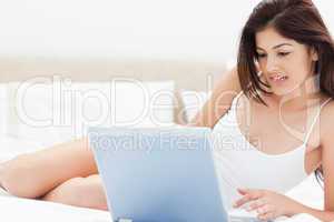 Woman lying on bed while watching and enjoying whats on her lapt