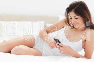 Wide Angle, woman using her smartphone while lying on her bed