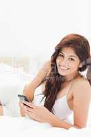 Woman looking ahead as she smiles and holds her smartphone, whil