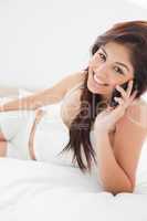 Close up, woman smiling and making a phone call from her bedroom