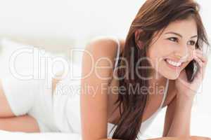 Woman relaxing on her bed making a phonecall as she lies forward