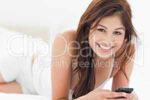 Woman smiles looking forward as she holds her smartphone while s