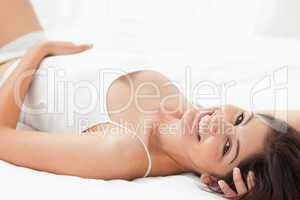 Woman lying on her back on the bed, smiling