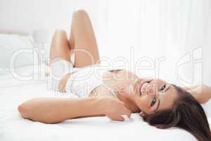 Woman lying on her back on the bed, her arms by her head and kne