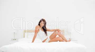 Wide Angle, Woman sitting across the bed with knee raised, showi