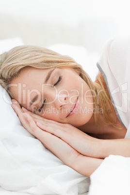 Close up, woman asleep with hands beside her head resting on a p