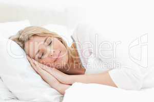 Woman sleeping in bed, hands positioned beside her face