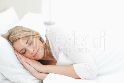 Woman resting in bed, with hands by her head