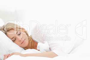 Woman sleeping in bed, with her arm resting slightly in front of