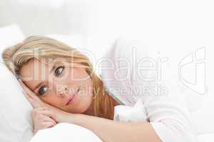 Woman resting in bed, eyes open and glancing just ahead of her