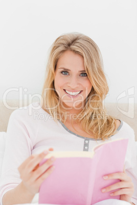 Close up, Woman smiling with book in hand, sitting in bed