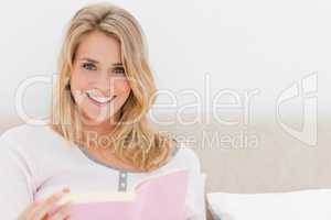 Woman looking forward with book in hand smiling