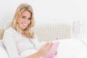 Side angle shot, Woman holding book, sitting in bed looking to t