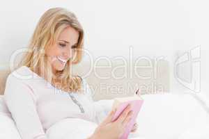 Side angle shot, Woman in bed, reading her book while smiling