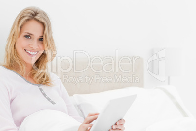 Closer shot, Woman in bed with tablet pc in hand, looking up and