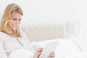 Closer shot, Woman in bed, using a tablet pc looking at the scre