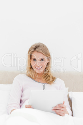 Centered shot, Woman sitting in bed with a tablet pc, looking ah