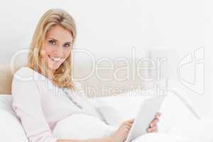 Woman looking up and to the side while smiling as she uses a tab