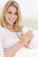 Close up, Woman in bed, with cup in hands as she looks forward s