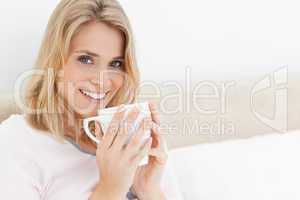 Woman holding a cup up to her lips, head turned  as she looks fo