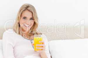Woman looking forward and smiling with a glass of orange juice i