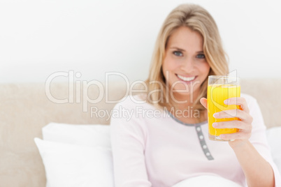 Woman holding a glass of orange juice while smiling and looking