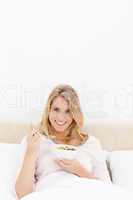 Vertical shot, Woman in bed with a bowl and spoon of cereal, smi